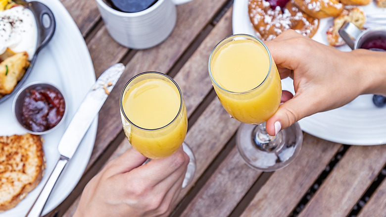 Hands holding mimosas