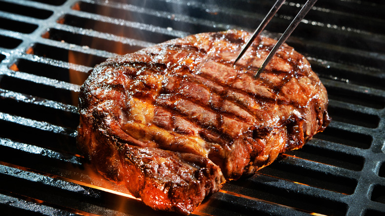 Browned, juicy steak on grill over flames