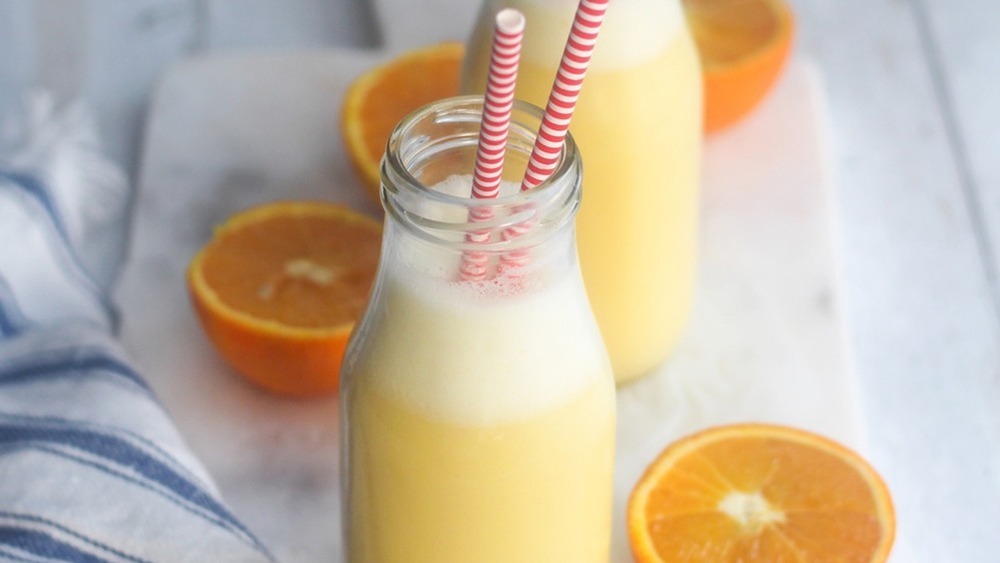 glass bottles filled with orange julius with two straws