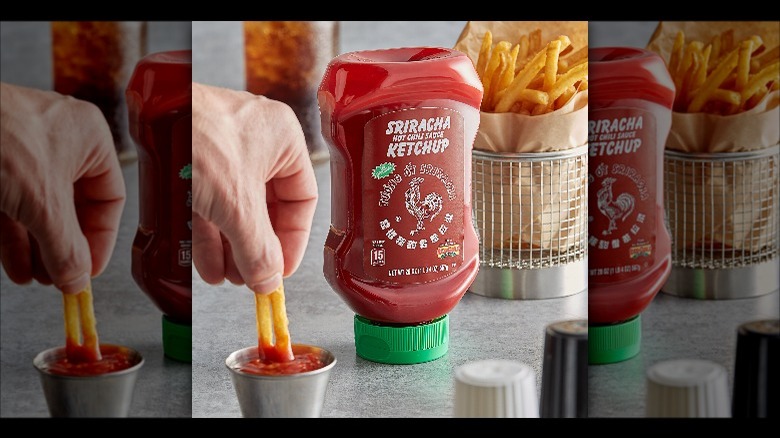 A bottle of Siracha Ketchup, with someone dipping thier fries into it