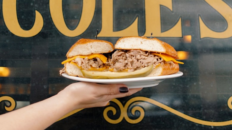 person holding French dip sandwich