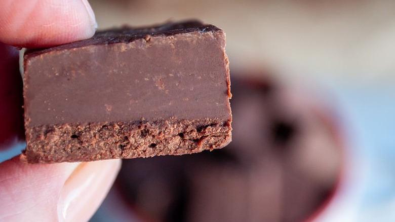 Fingers holding a square of chocolate fudge.