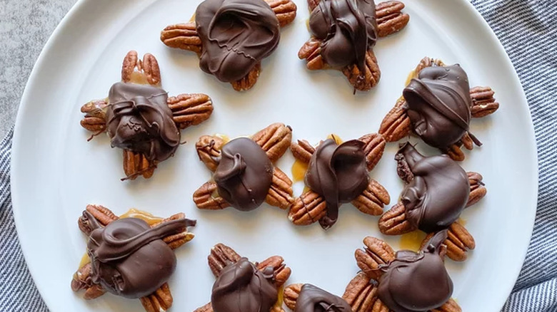 Chocolate, caramel, and pecan turtle candies on a plate.