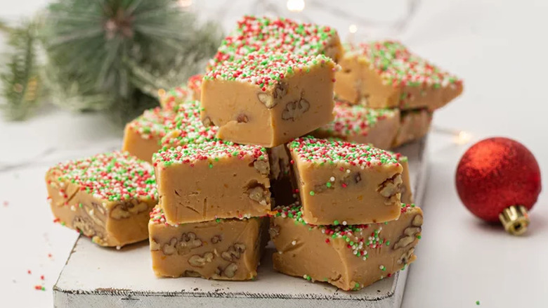 Cubes of light brown nut fudge with holiday sprinkles.