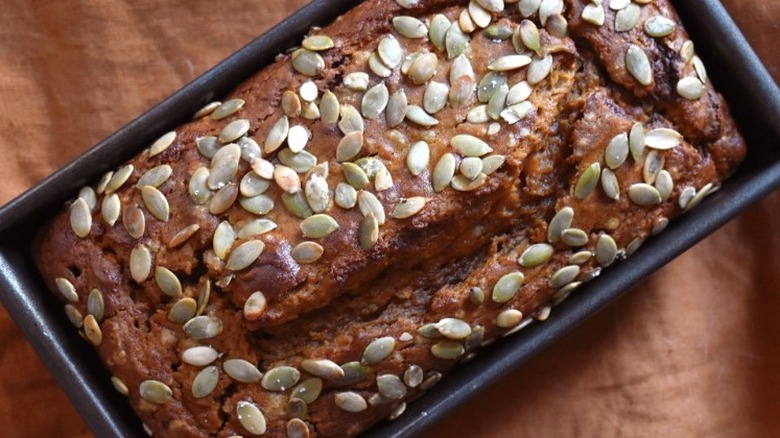 Baked pumpkin bread loaf with pumpkin seeds.