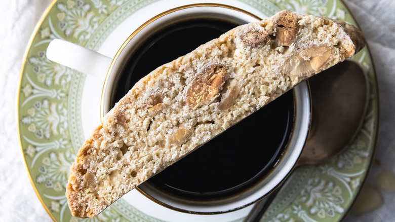 Biscotti cookie on coffee-filled cup.