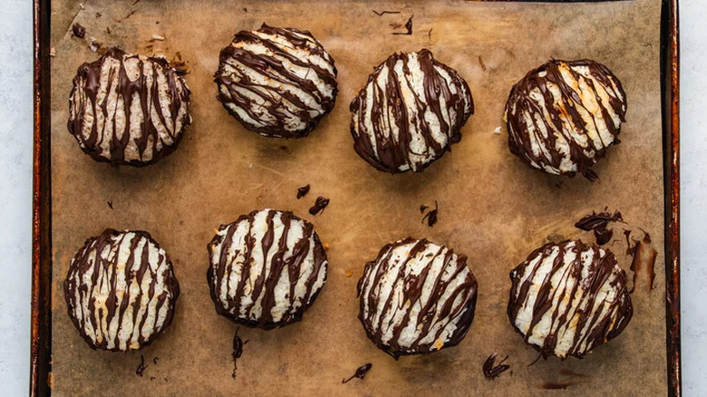 Round coconut macaroons on tray drizzled with chocolate.