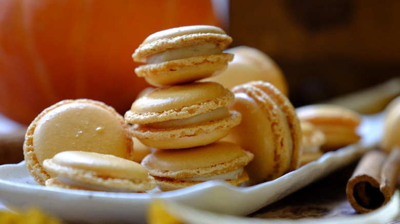 Stack of light orange, filled pumpkin macaron cookies.