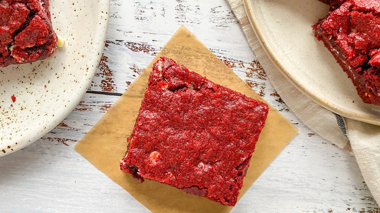 Square, red brownie on parchment paper.