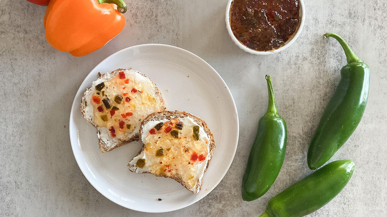 Pepper jelly on cream cheese toast with peppers around.