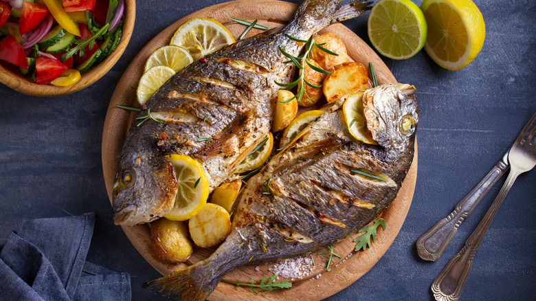 Roasted fish and potatoes, served on wooden tray.