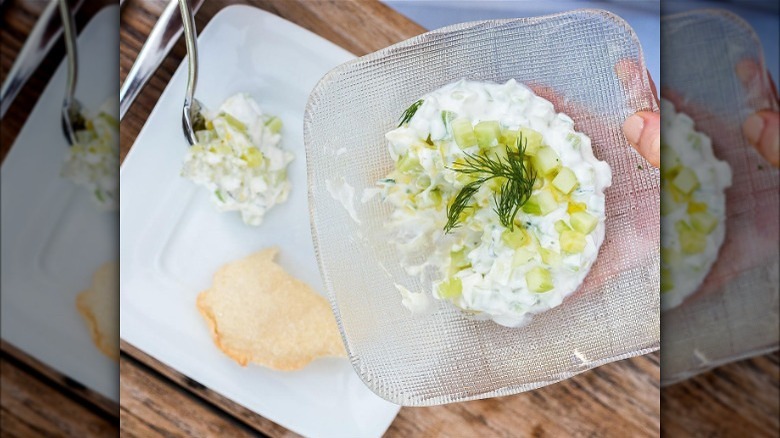 Tzatziki sauce in glass dish with spoon and pita