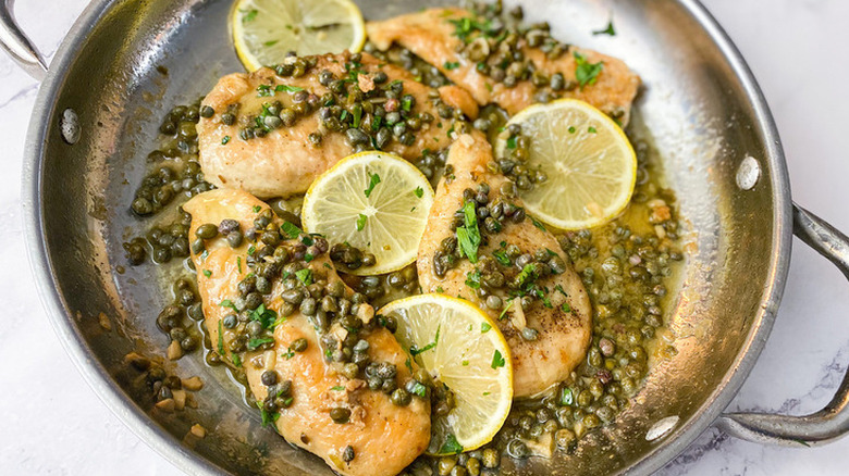 Pan with chicken breasts, capers, and lemons