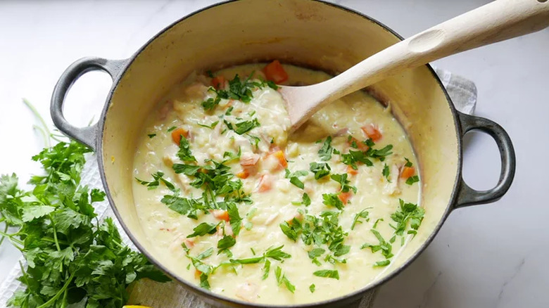 Pot of creamy soup with parsley and lemon