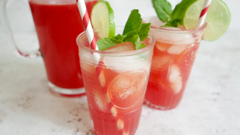 Glasses of red drink with mint and straws