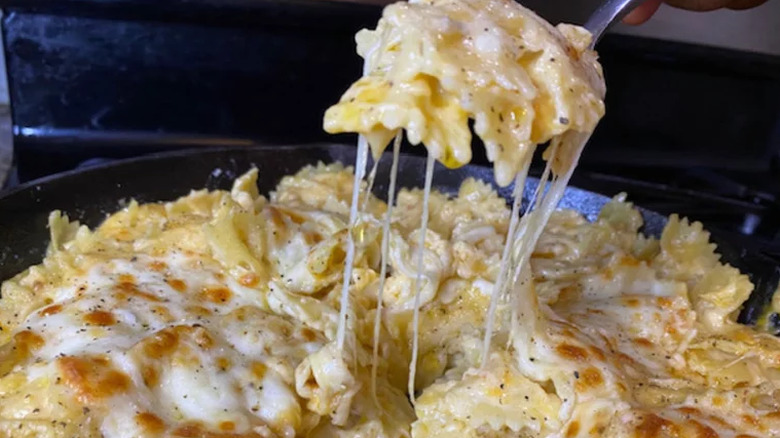 Pan of bowtie pasta covered with melted cheese. 