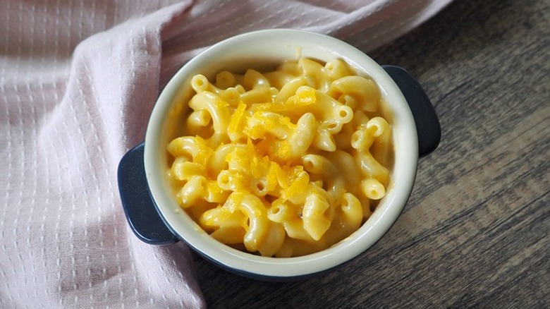 Small crock with mac and cheese and grated cheese on top.