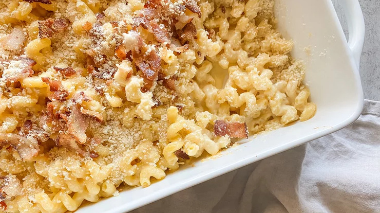 Baked mac and cheese with bacon in a white baking dish.