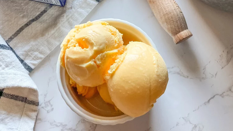 Scoops of bright orange ice cream in a small bowl.