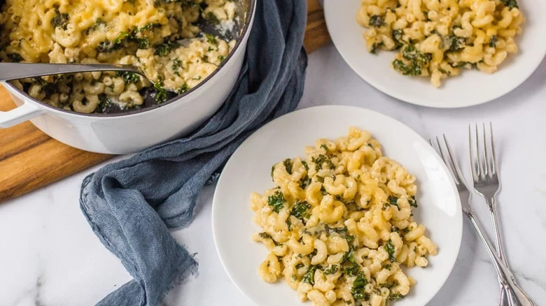 Pot and plates of mac and cheese with kale. 