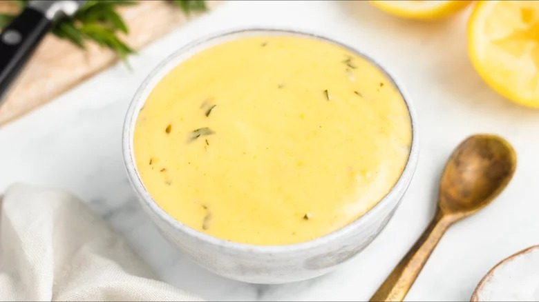 Béarnaise sauce in white bowl with metal spoon