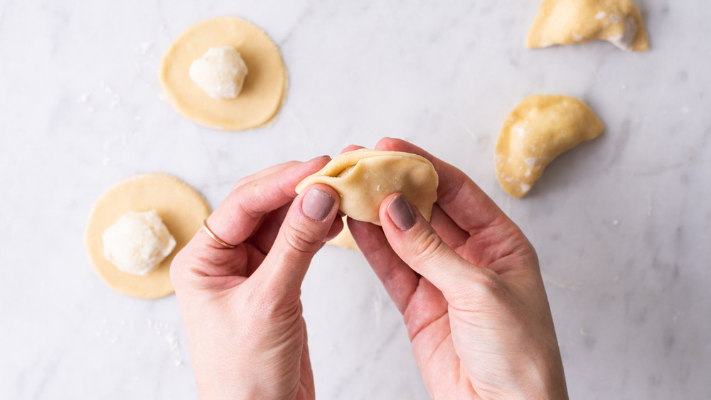 person folding homemade pierogies