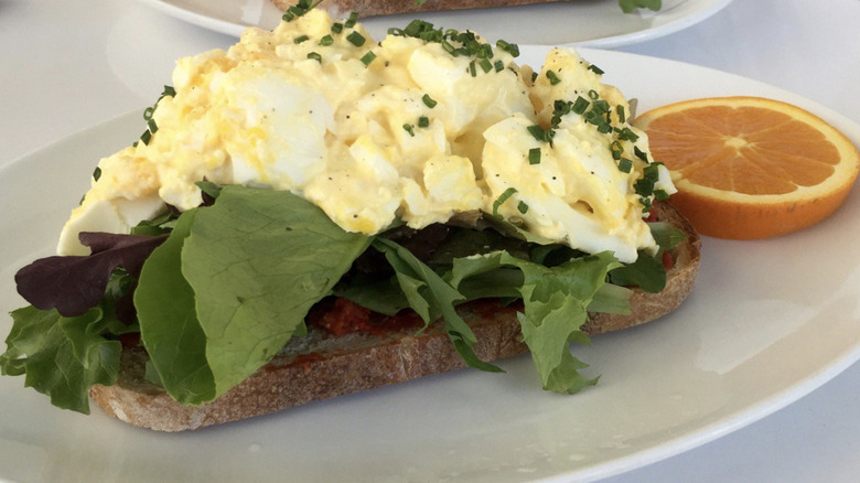 Open face egg salad sandwich with orange slice 