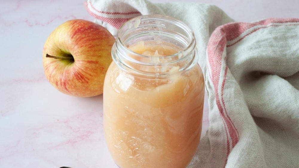 Applesauce in a jar with a fresh apple