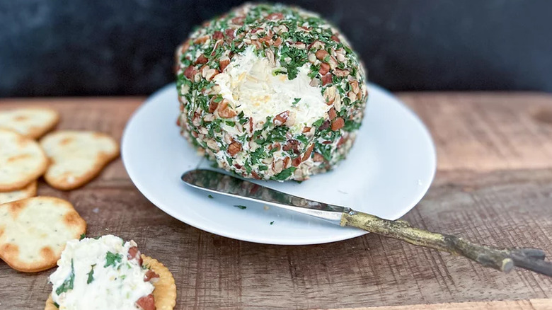 Cheese ball appetizer on plate with knife and crackers. 