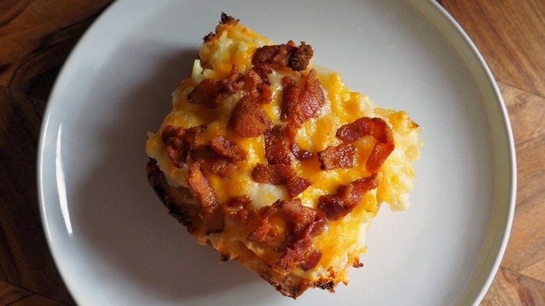 Slice of hashbrown casserole with bacon and melted cheese.