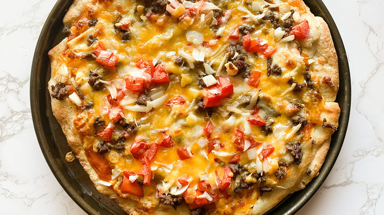 Round pizza with cheese, beef, and tomatoes.