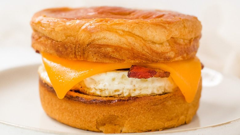 Breakfast sandwich with croissant bun, egg, and cheese.