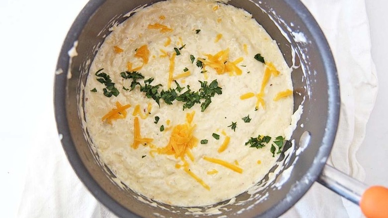 Pot with grits, herbs, and shredded cheese.