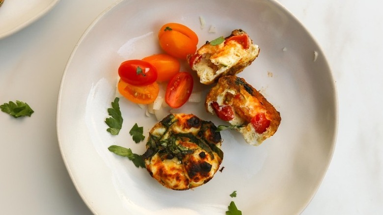 Small vegetable quiches on plate with cherry tomatoes.