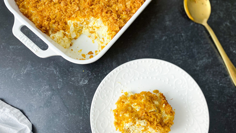 Casserole and small plate with cheese and potato casserole.