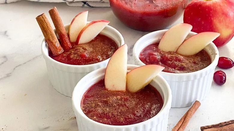 ramekins of cranberry applesauce with apple slices cinnamon sticks