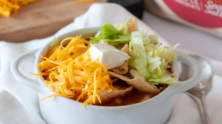 bowl of instant pot taco soup with cheese lettuce sour cream spoon