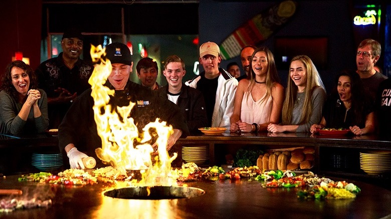 A chef grilling food while customers watch