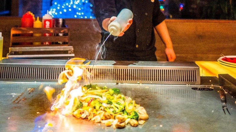 A chef at Flame grilling veggies with oil