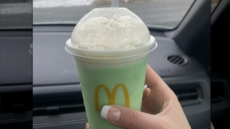 woman's hand holding a McDonald's shamrock shake