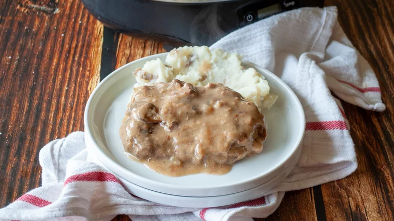 Cube steak with gravy and mashed potatoes on a white plate,