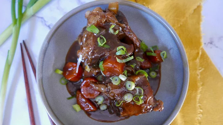 Cooked short ribs with gravy, carrots, and green onions. 