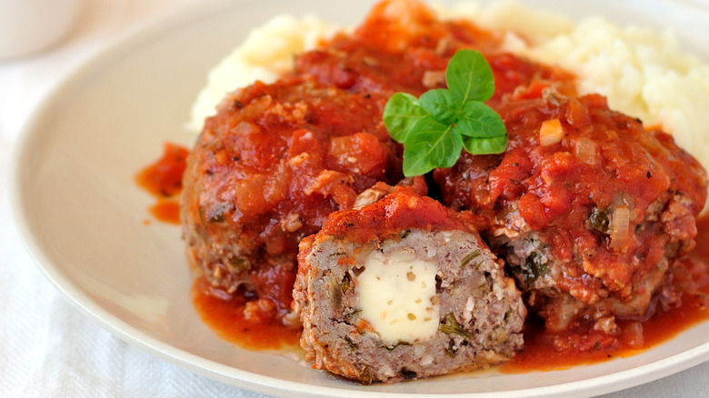 Meatball stuffed with cheese under tomato sauce.