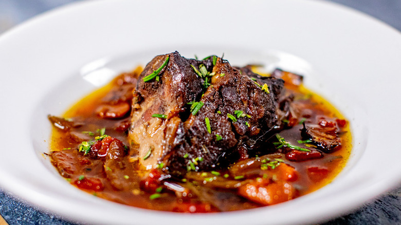 Pot roast in sauce in a shallow white dish.