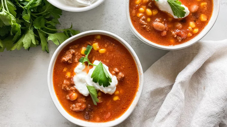 Small white bowls of taco soup with cream and cilantro.