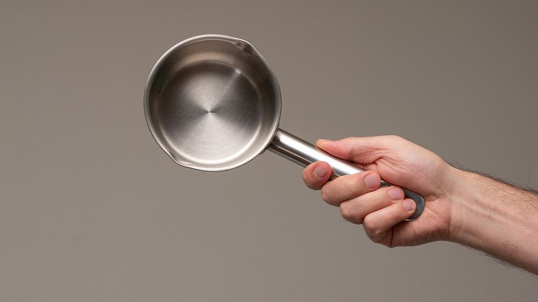 hand holding small saucepan