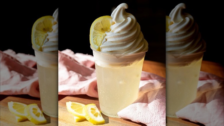 a cup filled with lemon soda and topped with vanilla ice cream garnished with a slice of lemon