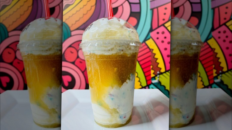 A red bull float with boozy ice cream in a plastic cup