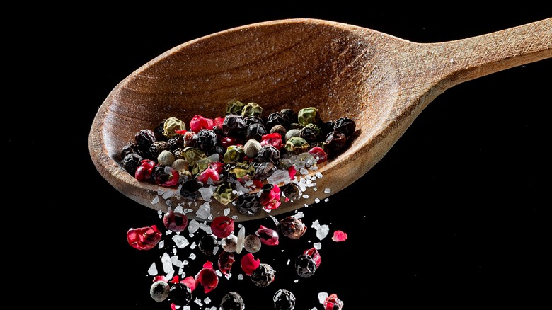 peppercorns falling out of wooden spoon