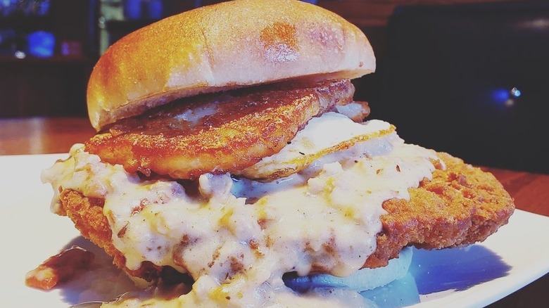 Chicken fried steak sandwich with fried egg and hash browns topped with gravy